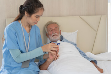 Obraz premium Asian nurse caregiver checking senior man oxygen with pulse oximeter. Patient resting and recovery on bed. Therapist take care and examine grandfather in nursing home. healthcare and medical insurance