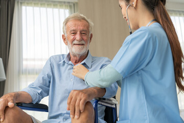 Nurse caregiver using stethoscope checking on heartbeat examining of senior man sitting on wheelchair, Happy grandfather smile and enjoy life after retirement. Therapist take care and support hime