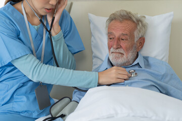 Asian nurse using stethoscope checking on heartbeat examining of senior man. Patient resting and recovery on bed. caregiver taking care grandfather in nursing home. healthcare and medical insurance