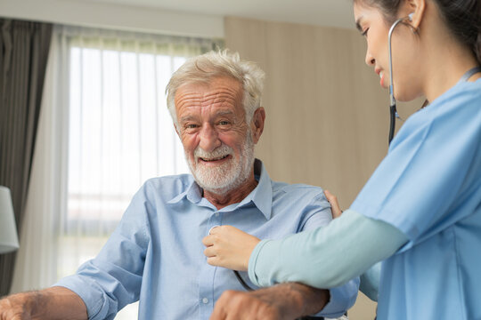 Nurse caregiver using stethoscope checking on heartbeat examining of senior man sitting on wheelchair, Happy grandfather smile and enjoy life after retirement. Therapist take care and support hime