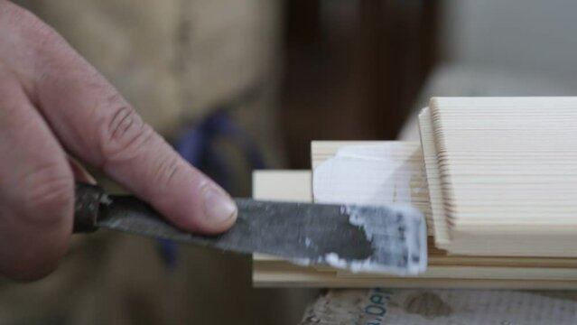 Carpentiere che applica colla su dettagli in legno con pennello. Lavori di falegnameria, preparazione e assemblaggio.