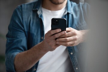 Portrait of an attractive smiling young man wearing casual clothes using mobile phone.