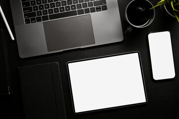 Modern black office desk workspace with laptop, smartphone and digital tablet mockup. top