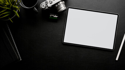 Minimal black working table top view with film camera, accessories, copy space and tablet