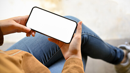A woman's hands are holding a mockup of a white smartphone screen in a horizontal position.