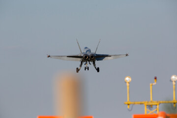 Warfare concept image. Modern jet fighter landing behind the runway lights. Image blurry due to engine heat waves.