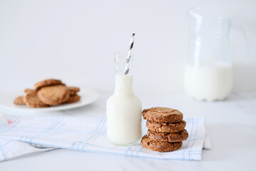 Glass jar of milk with a straw with homemade cookies on the background