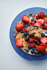Healthy breakfast in bowls with muesli, corn flakes, milk fresh raspberry, blueberries and strawberries. Health and diet concept
