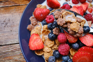 Healthy breakfast in bowls with muesli, corn flakes, milk fresh raspberry, blueberries and strawberries. Health and diet concept
