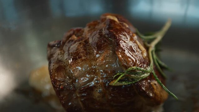 Close-up: Chef pouring sauce over filet mignon while cooking