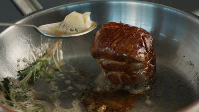 Close-up of a filet mignon being cooked in a frying pan