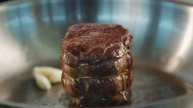 Close-up of a filet mignon being cooked in a frying pan