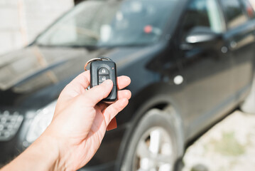 Close-up of human caucasian hand using car key remote control. Car alarm