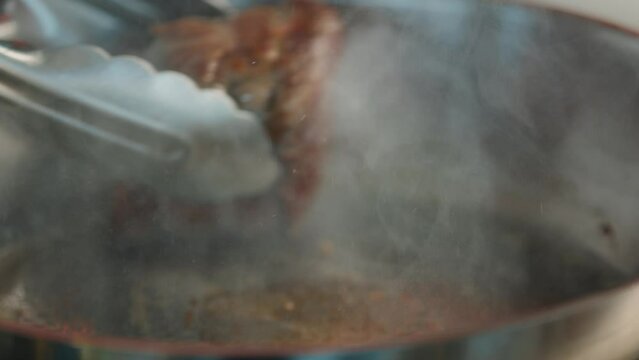 Close-up of a filet mignon being cooked in a frying pan
