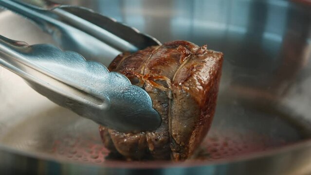 Close-up of a filet mignon being cooked in a frying pan