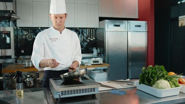 Chef pouring sauce over filet mignon while cooking in a professional restaurant kitchen