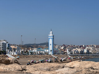 Crowd of people enjoying their summer holiday on the beach nearby Mohammed VI mosque in Fnideq