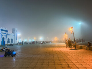  Crowd  of people walking in a public square on a foggy night