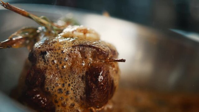 Close-up: Chef pouring sauce over filet mignon while cooking