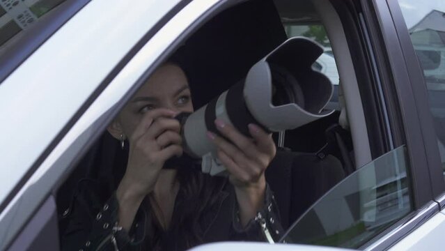 Young woman Paparazzi Photographer Capturing A Photo from car. Suspiciously Jealous wife Detective Spy Using A Big Professional Camera.