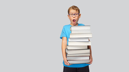 Boy carries a high stack of books - A lot of study material at school.