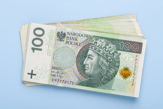 Stack of polish paper currency, 100 zloty PLN bills on blue background top view