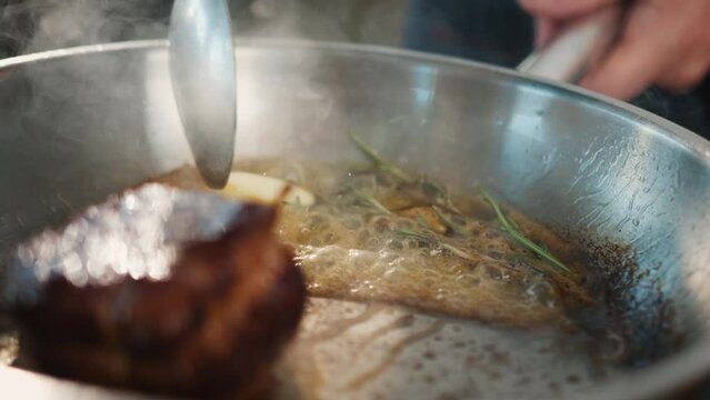 Close-up of filet mignon with thyme being cooked in a frying pan