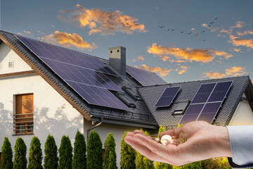 The concept of saving money and clean energy. Solar panel on the roof of a modern house and coins...
