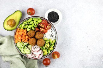 Salad with falafel, edamame beans, avocado, sesame, cherry tomatoes, radish on a gray background,...
