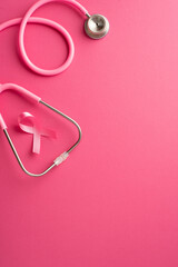 Top view vertical photo of pink ribbon symbol of breast cancer awareness and stethoscope on isolated pink background