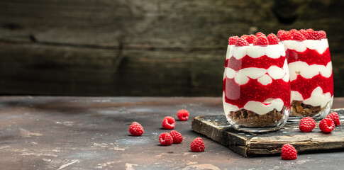 Cranachan raspberry dessert in jar on a dark background. Long banner format