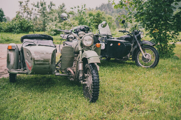 two old motorcycles with a sidecar in the countryside
