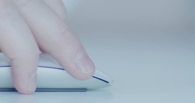 Hand Clicking a Computer Mouse A close-up of a person's fingers clicking a sleek white computer mouse on a clean desk. The minimalistic setting highlights technology, digital work