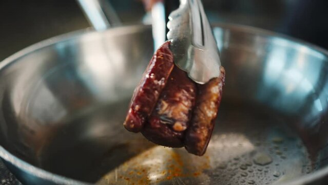 Close-up of a filet mignon being cooked in a frying pan