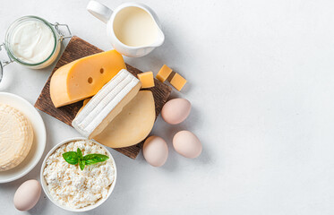 Different types of cheese, cottage cheese, sour cream and eggs on a gray background. Assortment of dairy products. Top view, copy space