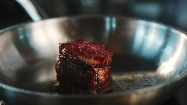 Close-up of a raw filet mignon being cooked in a frying pan