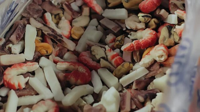Mix of frozen sea marine products by weight on sale in freezer refrigerator. Squid, shrimp, mussels, octopus. Seafood. Store shopping mall centre supermarket