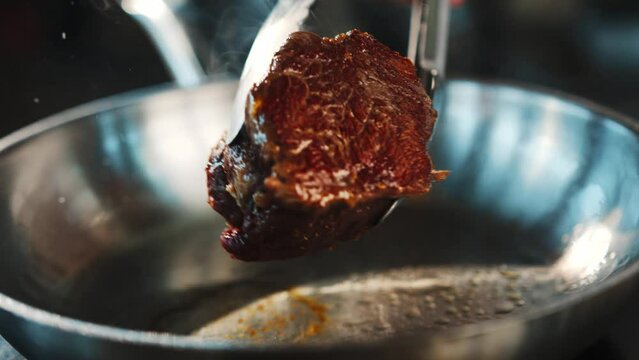 Close-up of a raw filet mignon being cooked in a frying pan
