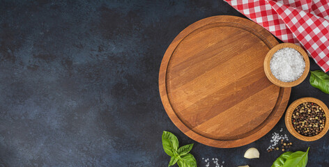 Wooden cutting board and spices, herb for food on black stone table