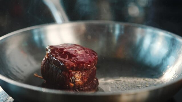 Close-up of a raw filet mignon being cooked in a frying pan
