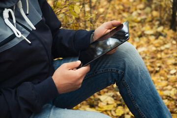 Man hipster using tablet in autumn forest during hiking trip. Travel concept, hike, fall season....