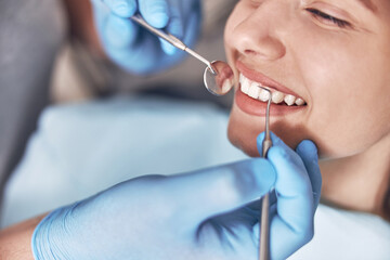 Confident mature doctor is checking teeth of young beautiful happy caucasian woman in modern clinic