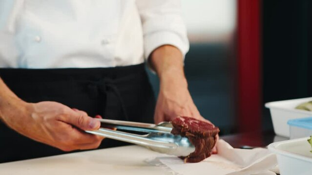 Close-up: The chef puts raw filet mignon on a frying pan