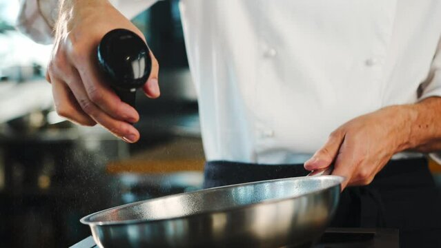 Close-up: Chef pouring oil on a frying pan before cooking