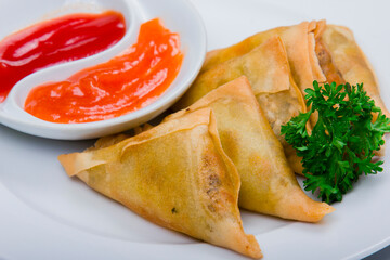 Spring rolls (lumpia) traditional Indonesian food with tomato and chili sauce served on a white plate