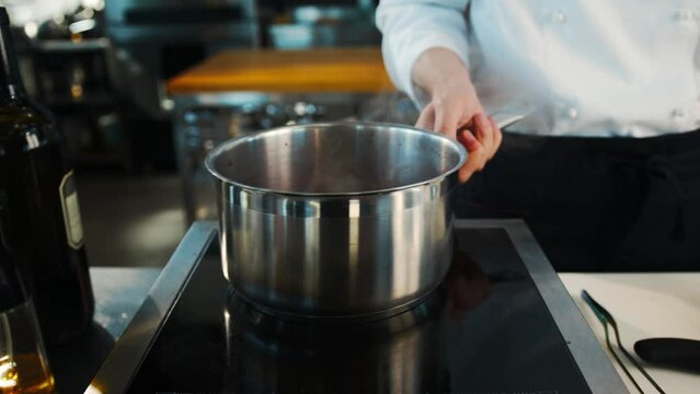 The chef makes sauce in saucepan in a professional restaurant kitchen. The process of food preparation.