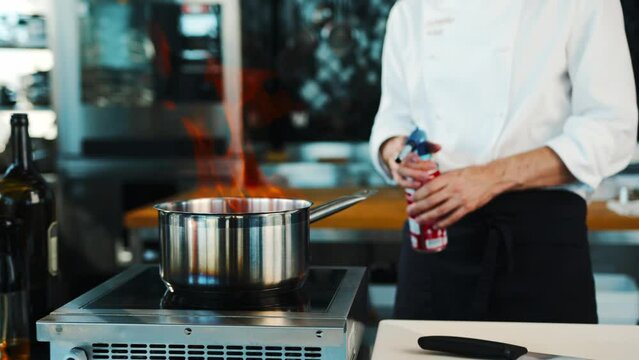 The chef sets fire to the dish in the professional kitchen of the restaurant. The process of cooking food with fire.