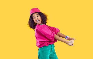 Fototapeta na wymiar Cheerful funny stylish african american teen girl having fun on vivid yellow background. Happy energetic kid girl in trendy bright colored clothes having fun and fooling around laughing out loud.