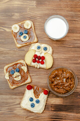 Funny cute bear,monkey,fox,owl faces sandwich toast bread with peanut butter,banana,blueberry,raspberry,milk. Kids childrens baby's sweet dessert healthy breakfast lunch food art,close up,top view