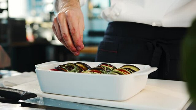 Close-up: The chef adds spices to ratatouille. The process of preparing food in a restaurant.